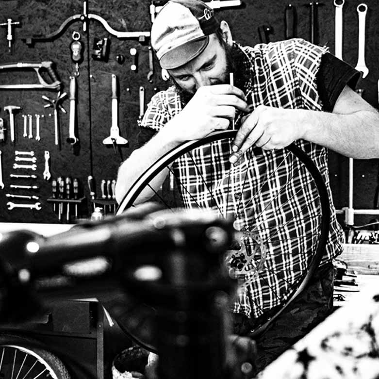 Mechanik rowerowy w warsztacie, zmieniający dętkę w rowerze.
